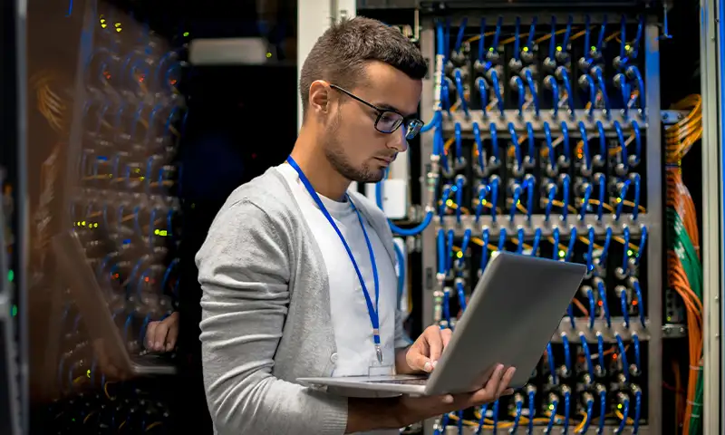 IT professional with laptop next to high-performance computing infrastructure